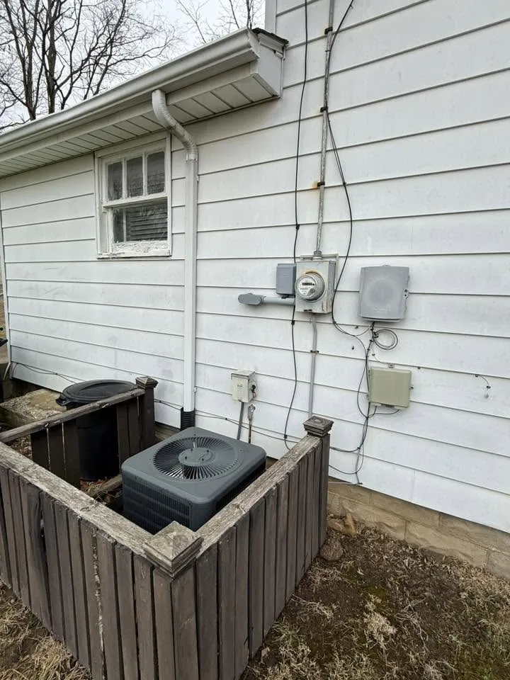 Before: an old round meter socket and weathered service equipment on the side of a white house