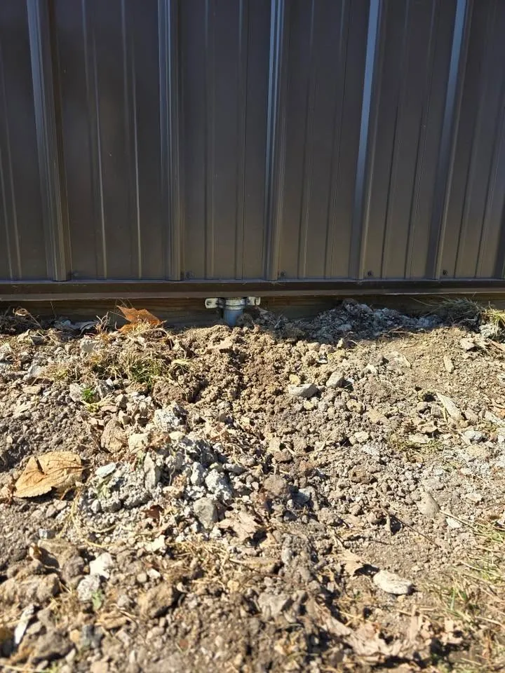 Conduit entering the base of a steel-sided pole building from below grade